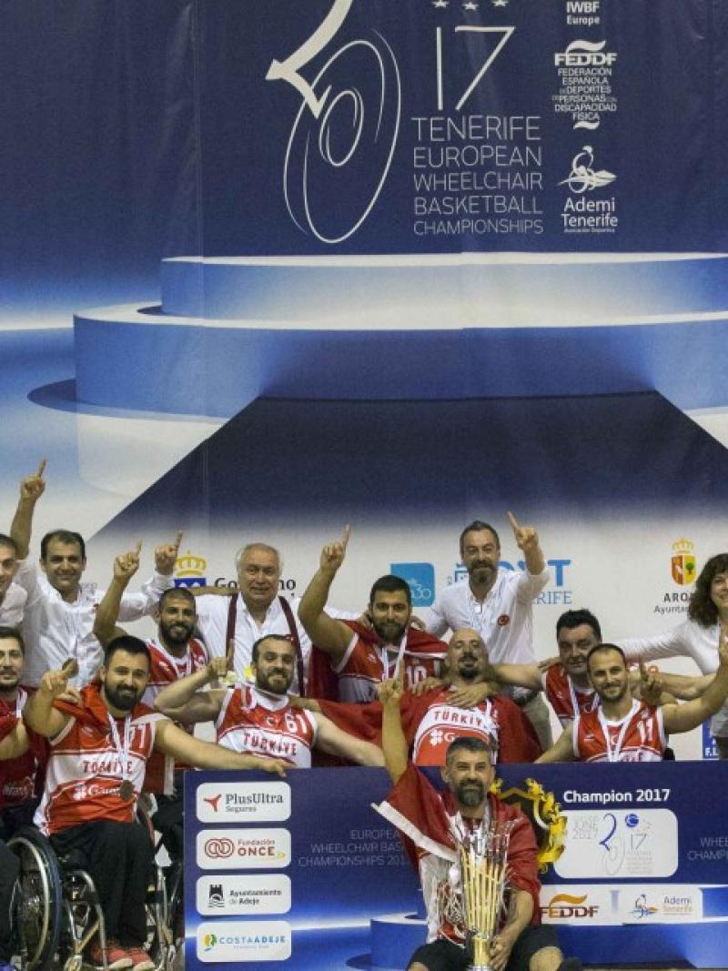 a group of men in wheelchairs celebrate with their trophy