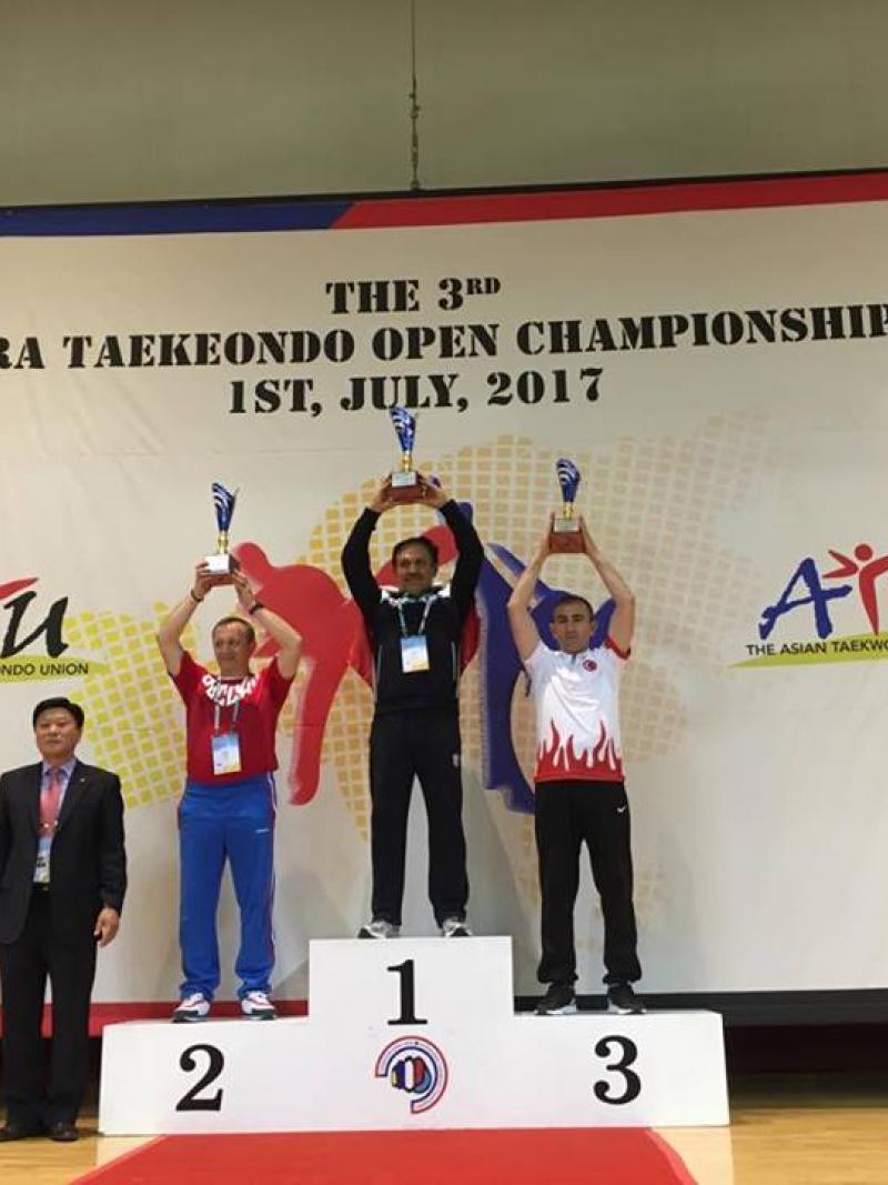 three men hold trophies on a podium