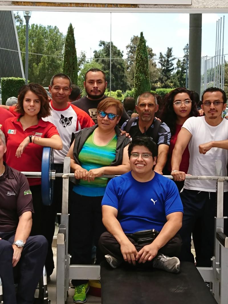 A group of men and women standing and in wheelchairs smile for the camera