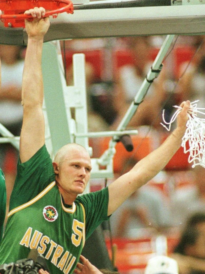A man hangs off a basketball hoop