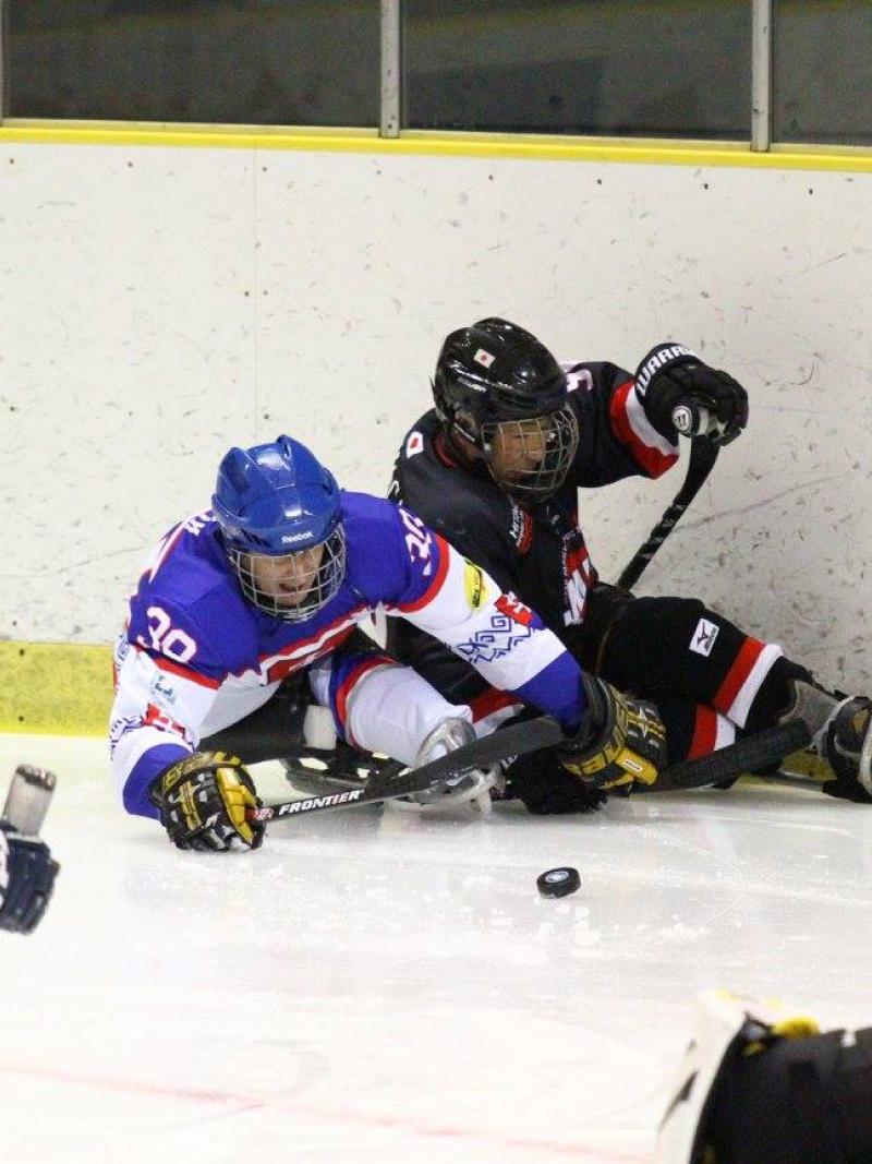 a group of para ice hockey players fight for the puck