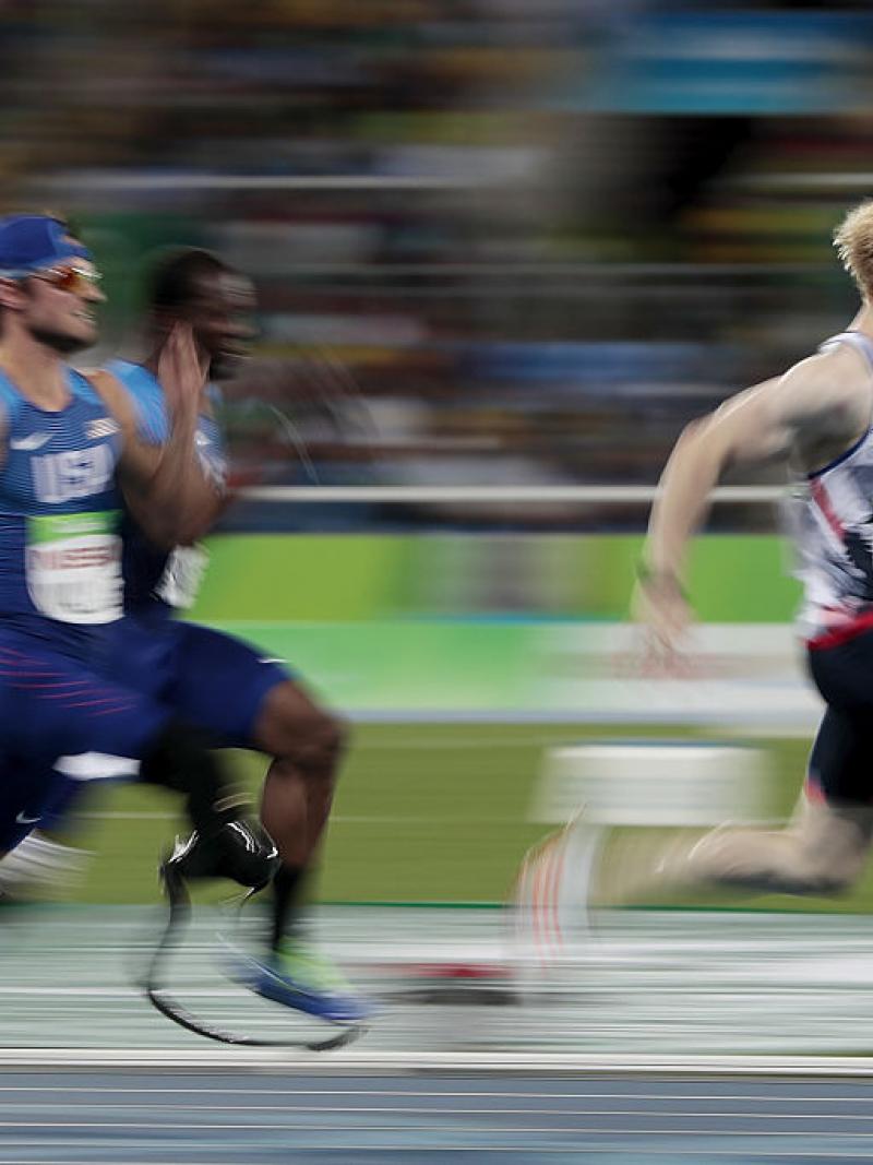 three para sprinters run towards the finish line