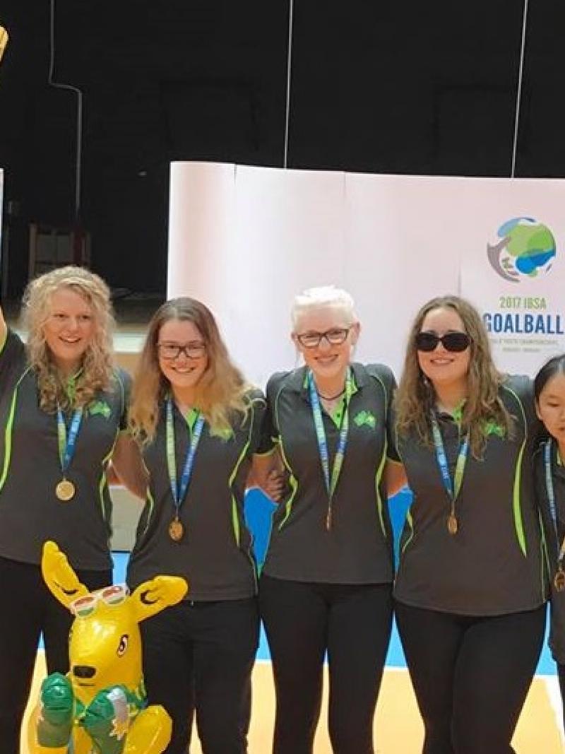 A group of female athletes celebrate with a trophy