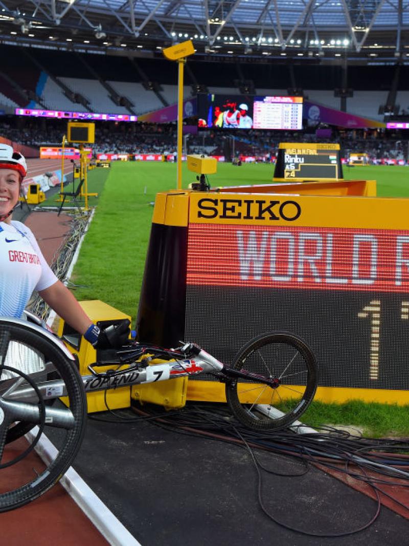 Woman in racing wheelchair next to a screen