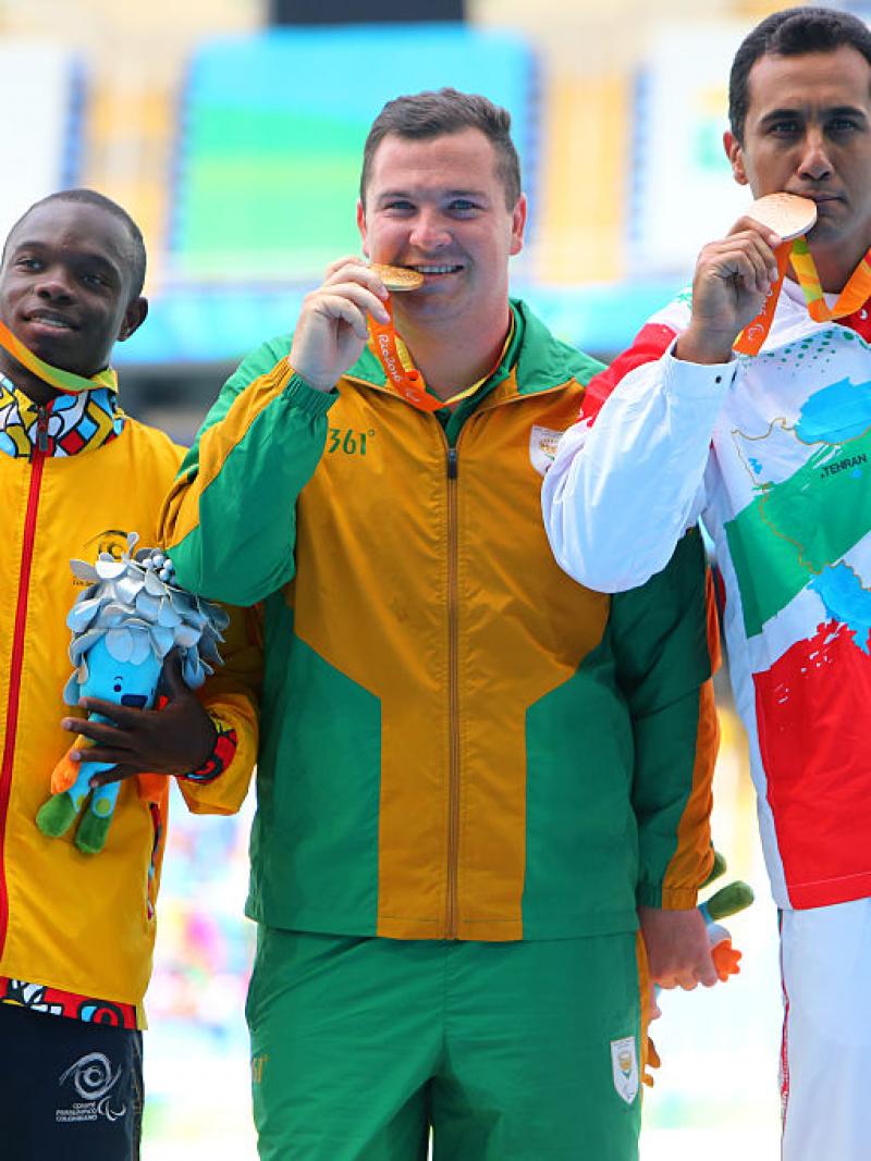 three men stand on a podium with their medals