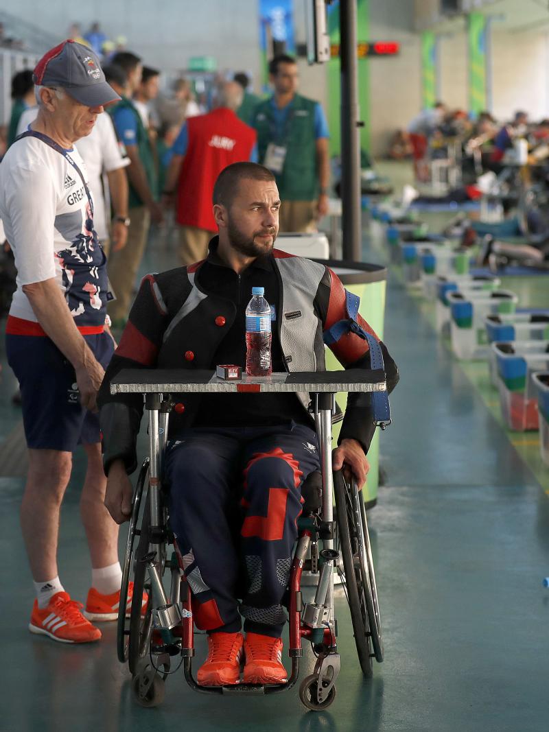 a para shooter in a wheelchair waits with his coach