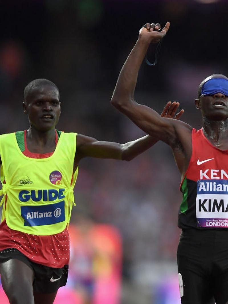 a blindfolded runner and his guide celebrate after crossing the finish line 
