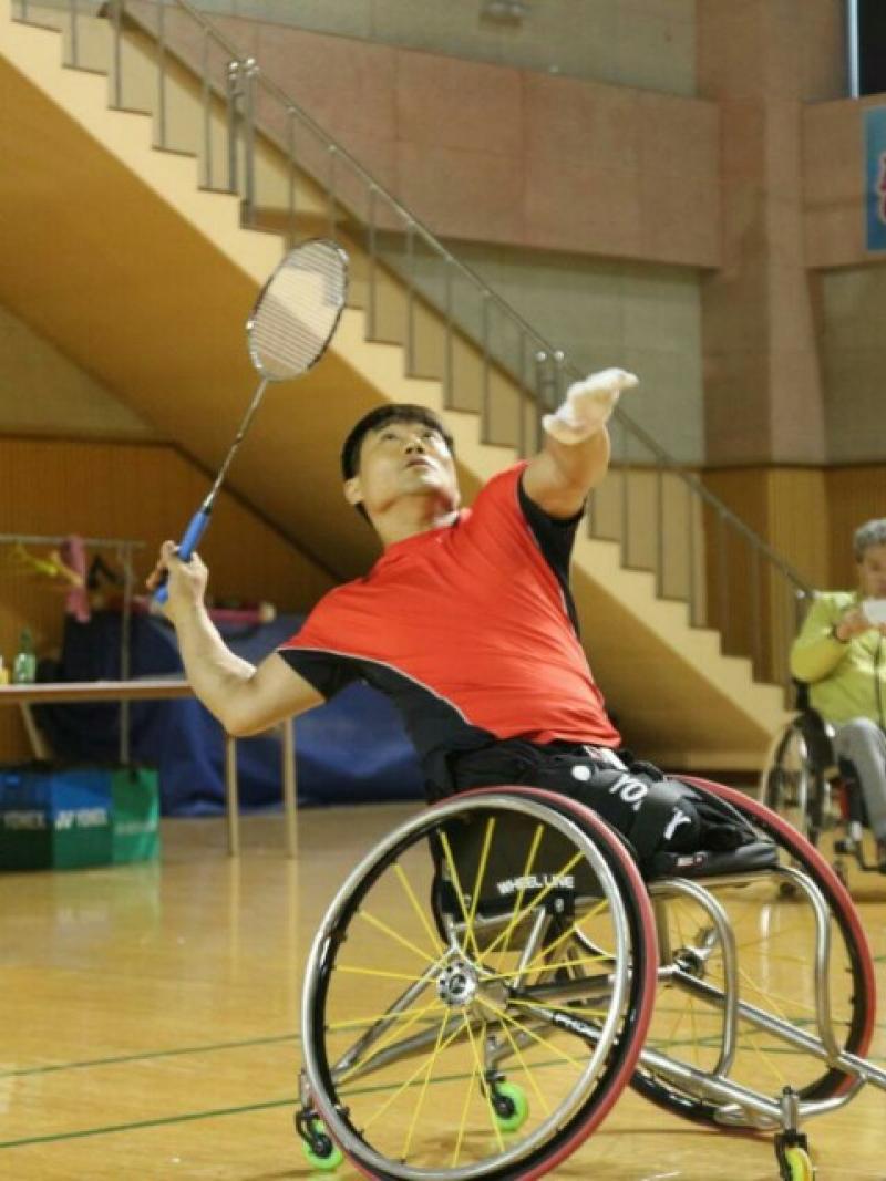 a para badminton player in a wheelchair goes for a shot