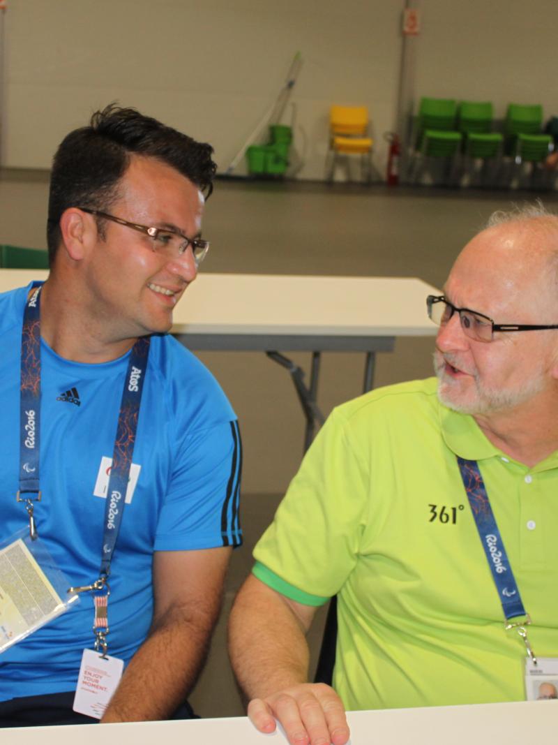 two men chat at a table