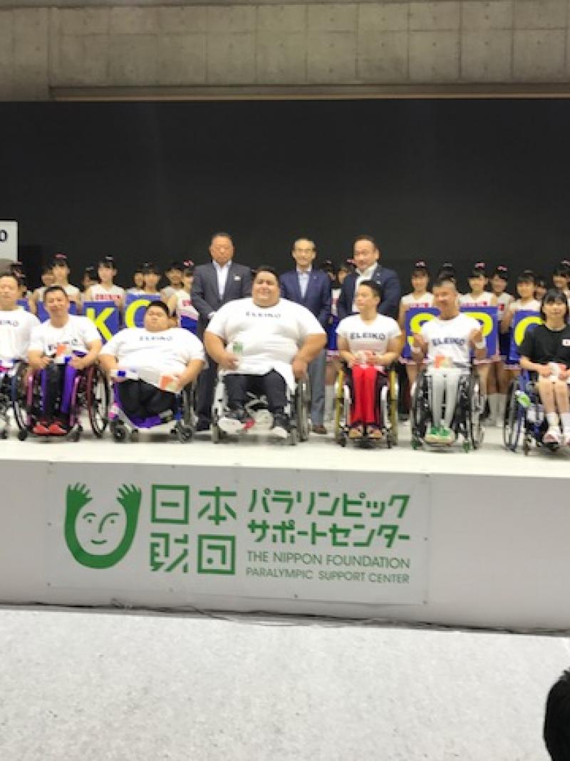 a Para powerlifter on a stage surrounded by young children