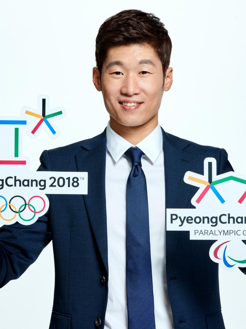 A man poses with the Olympic and Paralympic logos for PyeongChang 2018
