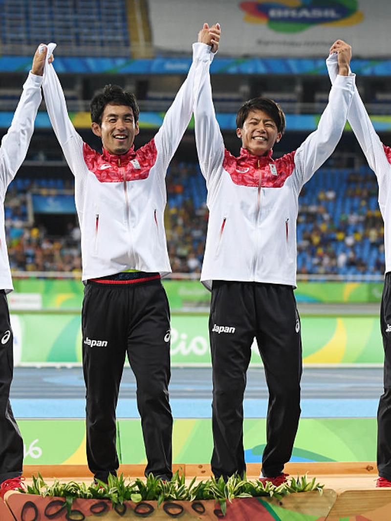 a group of four male Para athletes raise their arms in celebration
