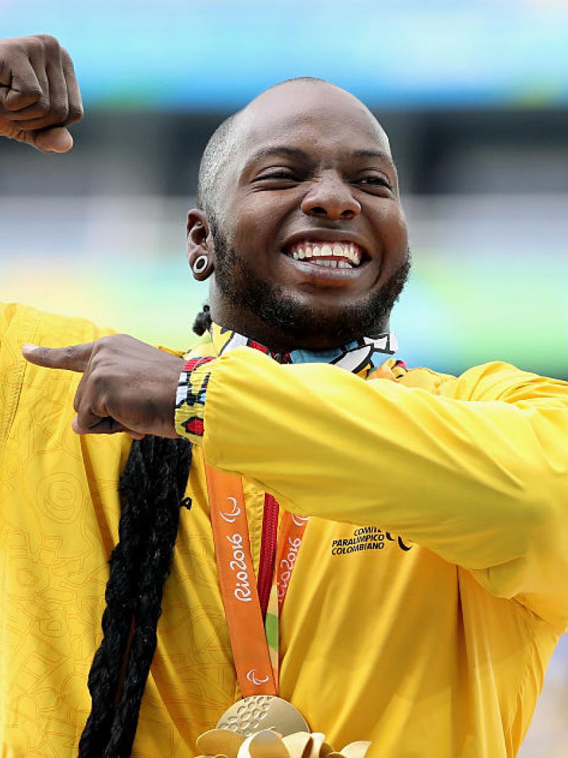 a man holds up his arms in celebration on the podium
