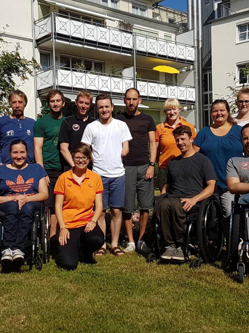 a group of officials and Para athletes smile for the camera