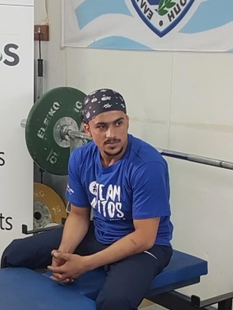 a male Para powerlifter sits on his bench