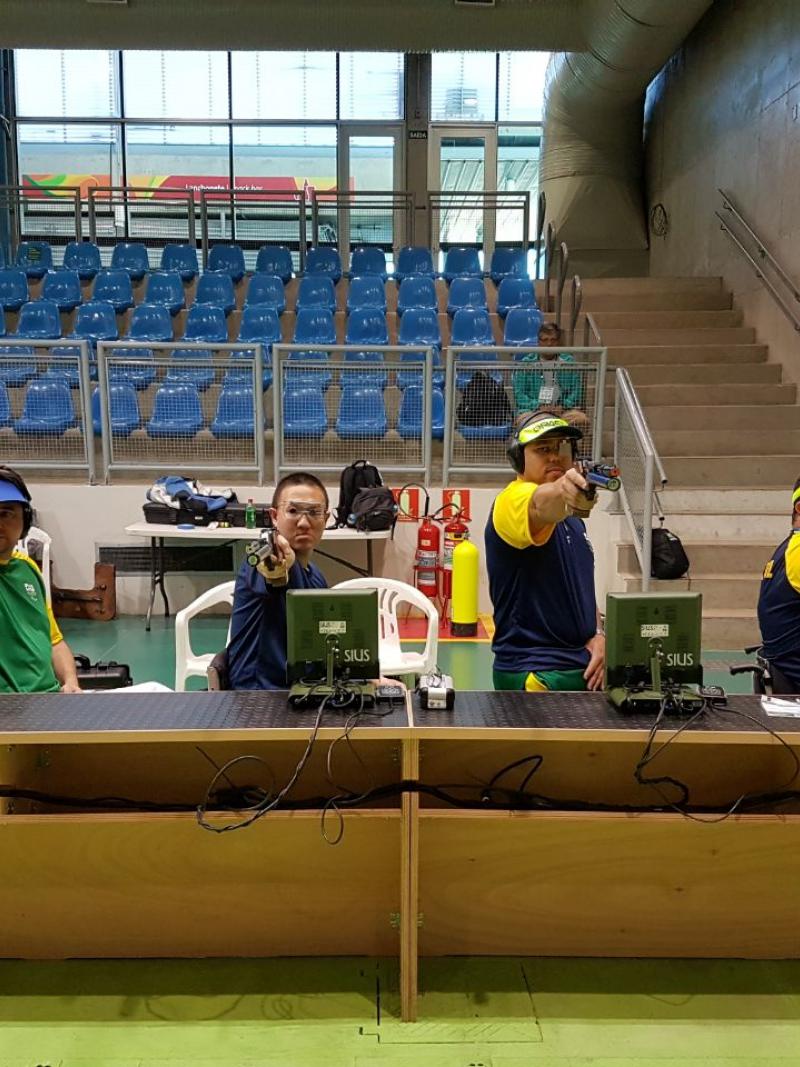 a row of male athletes compete with rifles in shooting Para sport