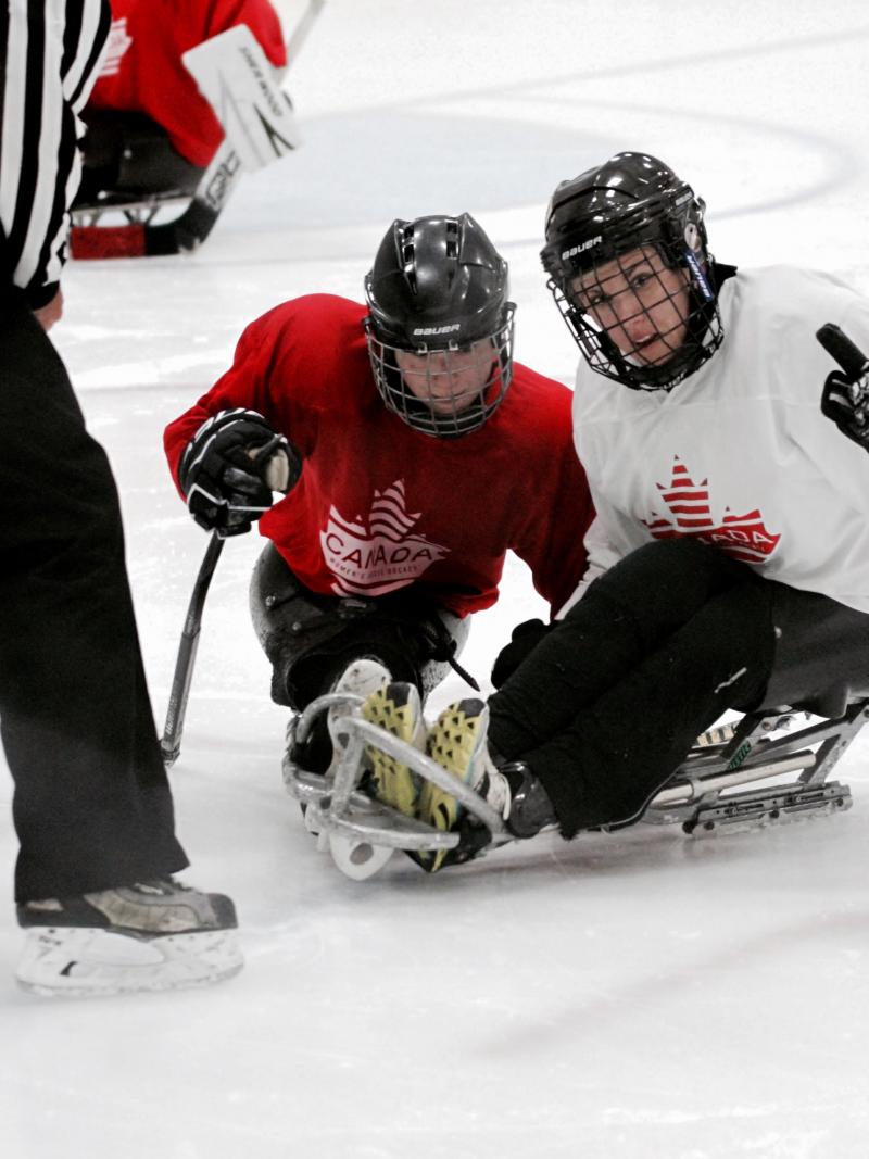 two female Para ice hockey players are given instructions on the ice