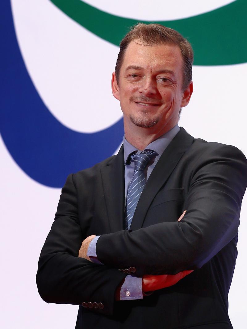 A man standing in front of the Agitos symbol