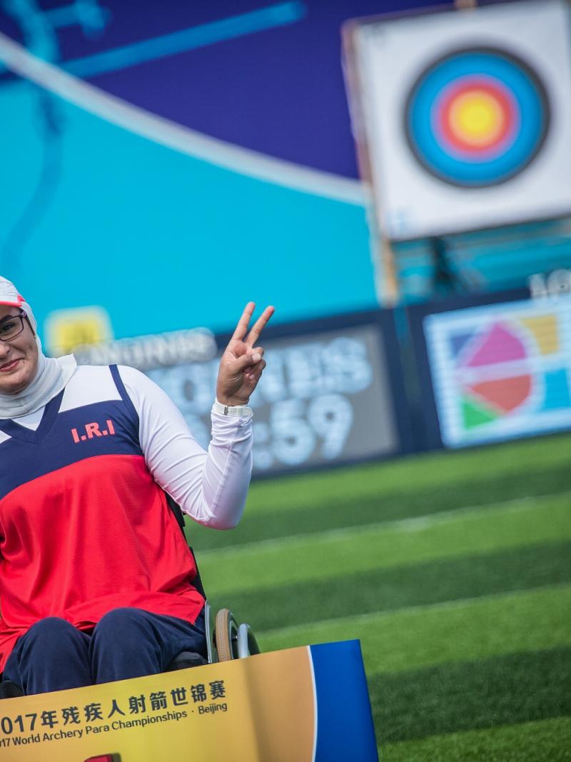 Female archer poses in front of a target