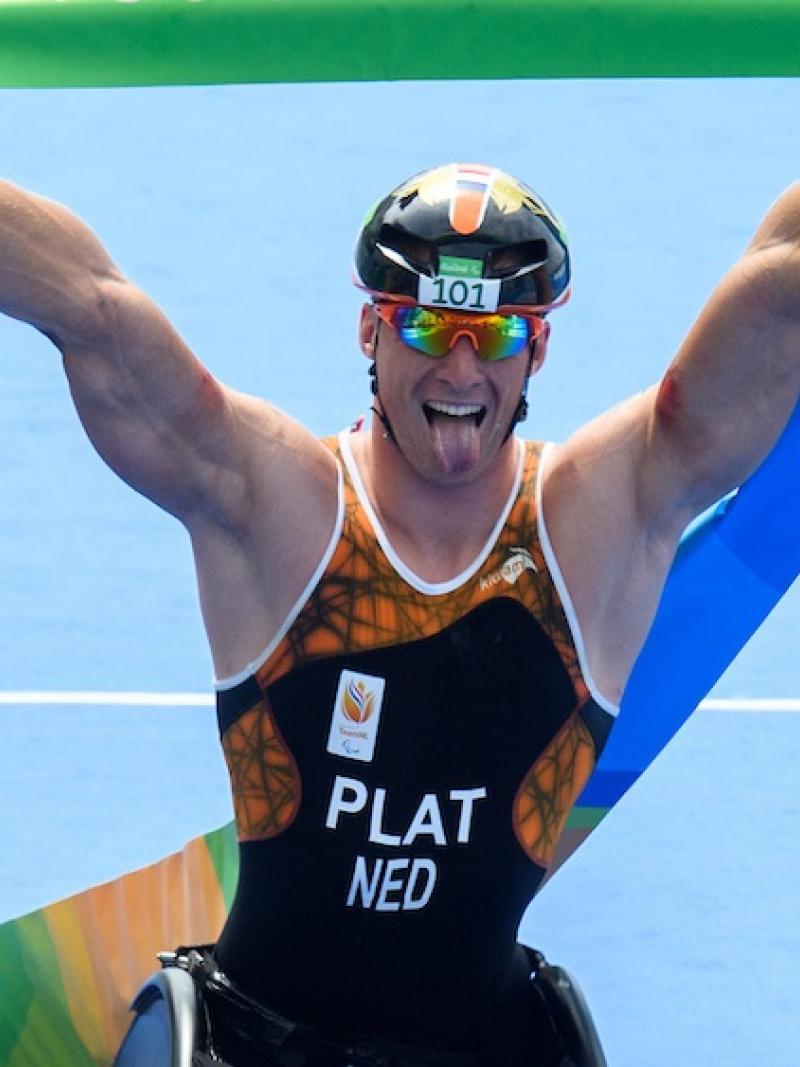 a Para athlete sticks his tongue out as he crosses the finish line