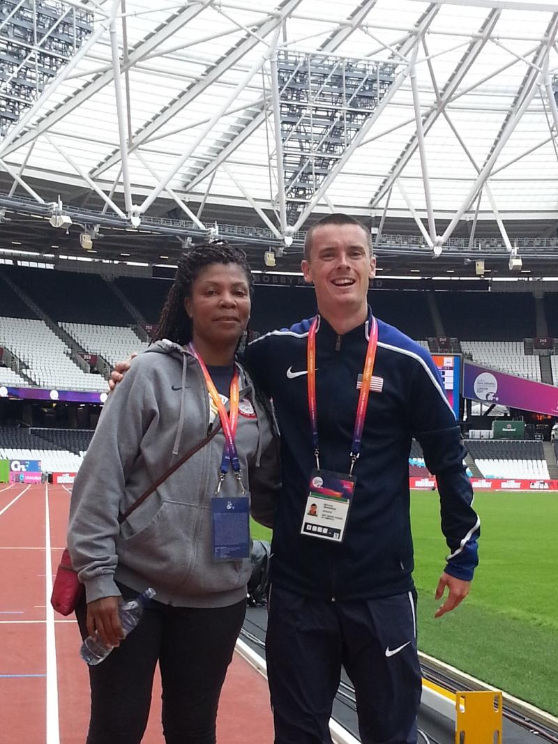 a female coach and male athlete stand together on the track at the London Stadium