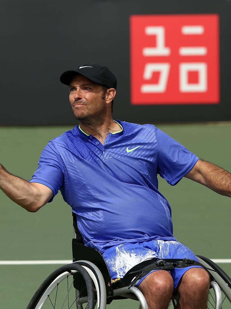 a male wheelchair tennis player hits a forehand