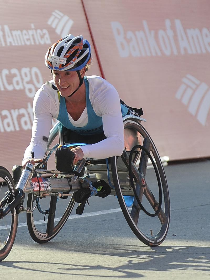 a female wheelchair racer celebrates crossing the line