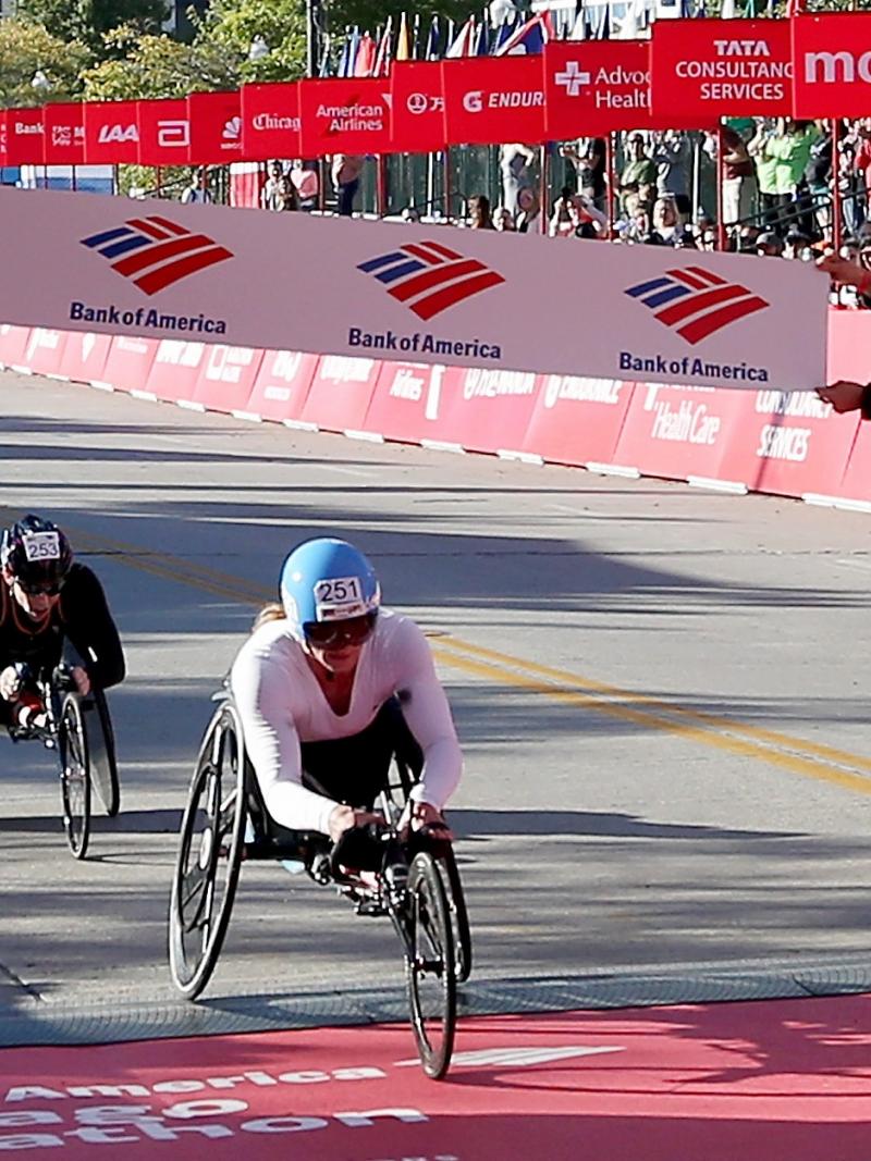 a female wheelchair racer crosses the finish line