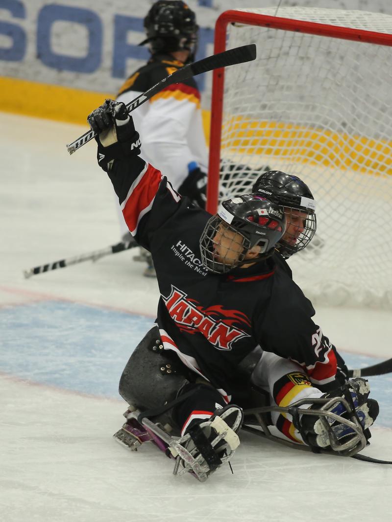 a Para ice hockey player raises his arm in celebration at a goal