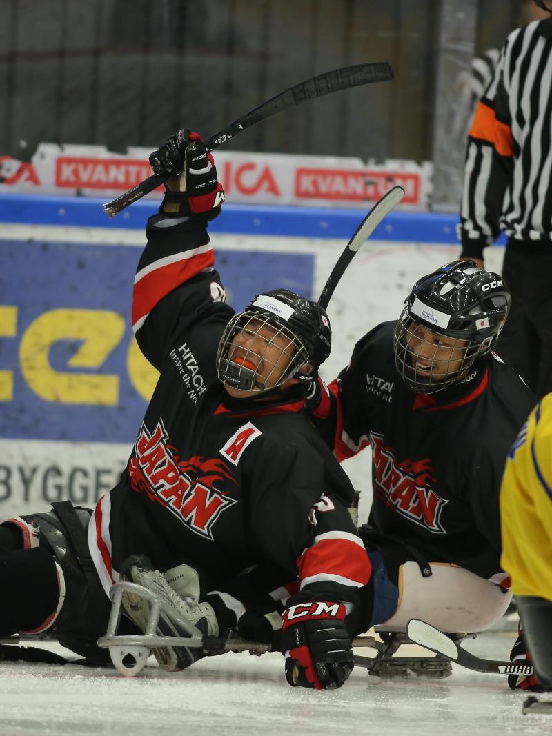 a group of Para ice hockey players celebrate a goal