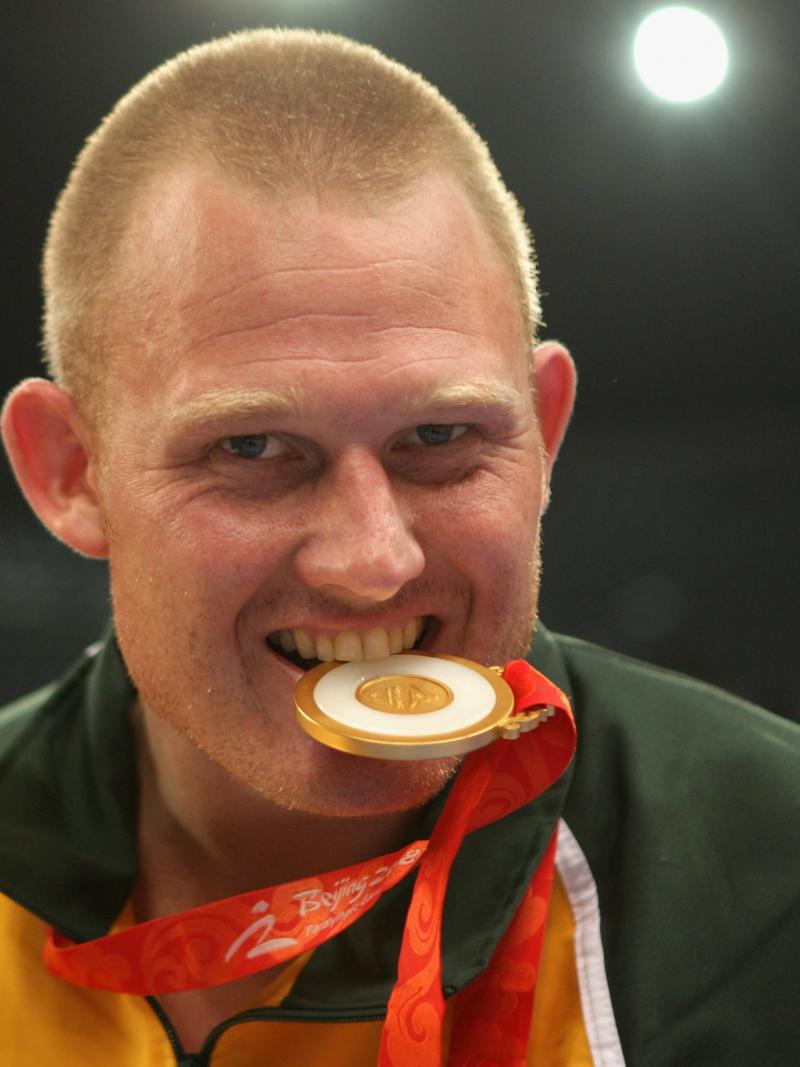 a male Para athlete bites his medal