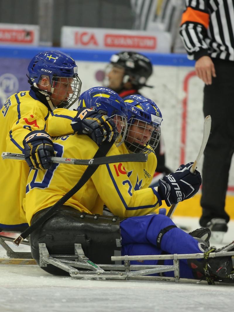 a group of Para ice hockey players celebrate on the ice