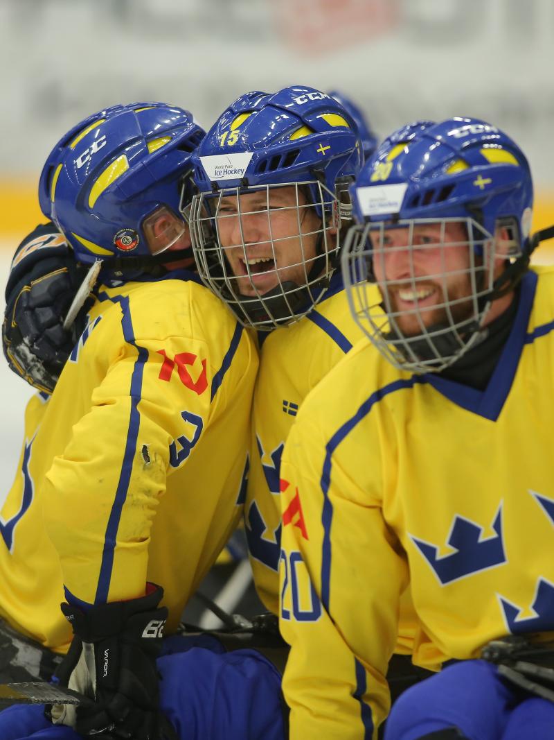 a group of Para ice hockey players hug on the ice