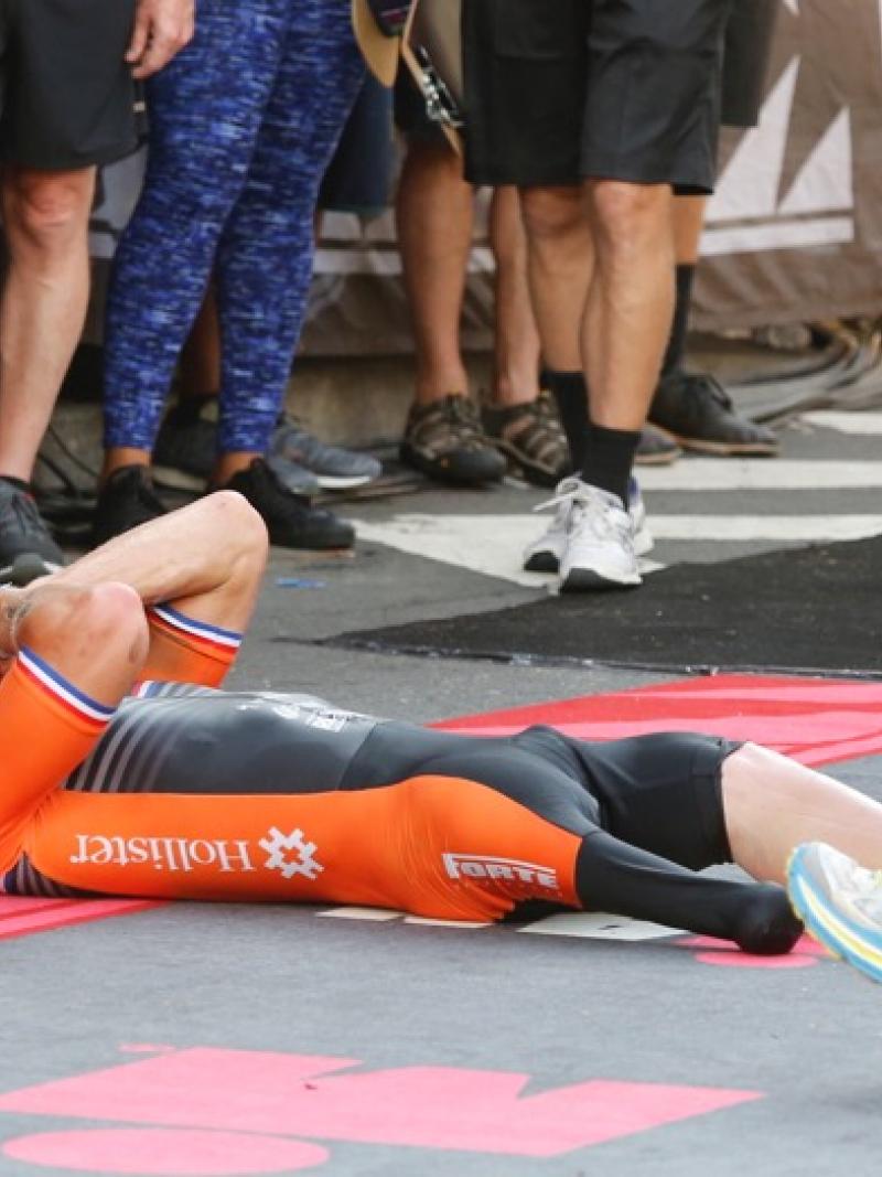 a man lies on the road celebrating after crossing the finish line