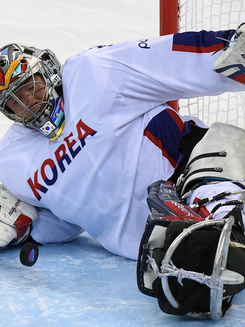 a male Para ice hockey player makes a save