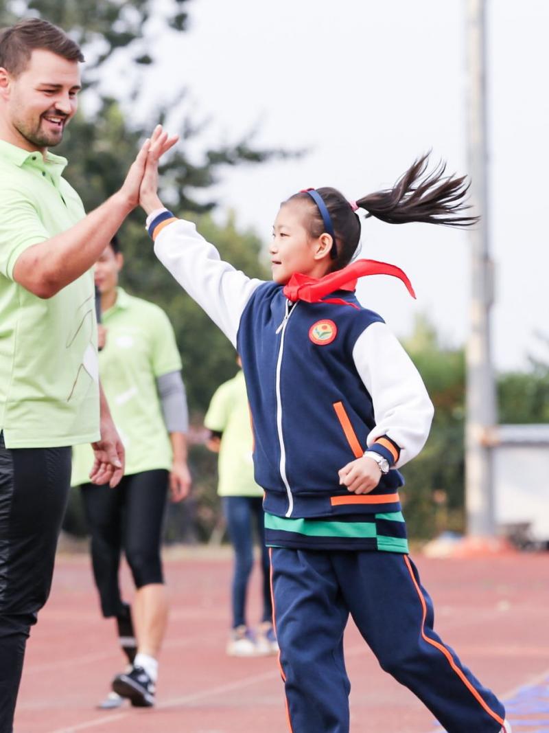 a male Para athlete high fives a girl on the track