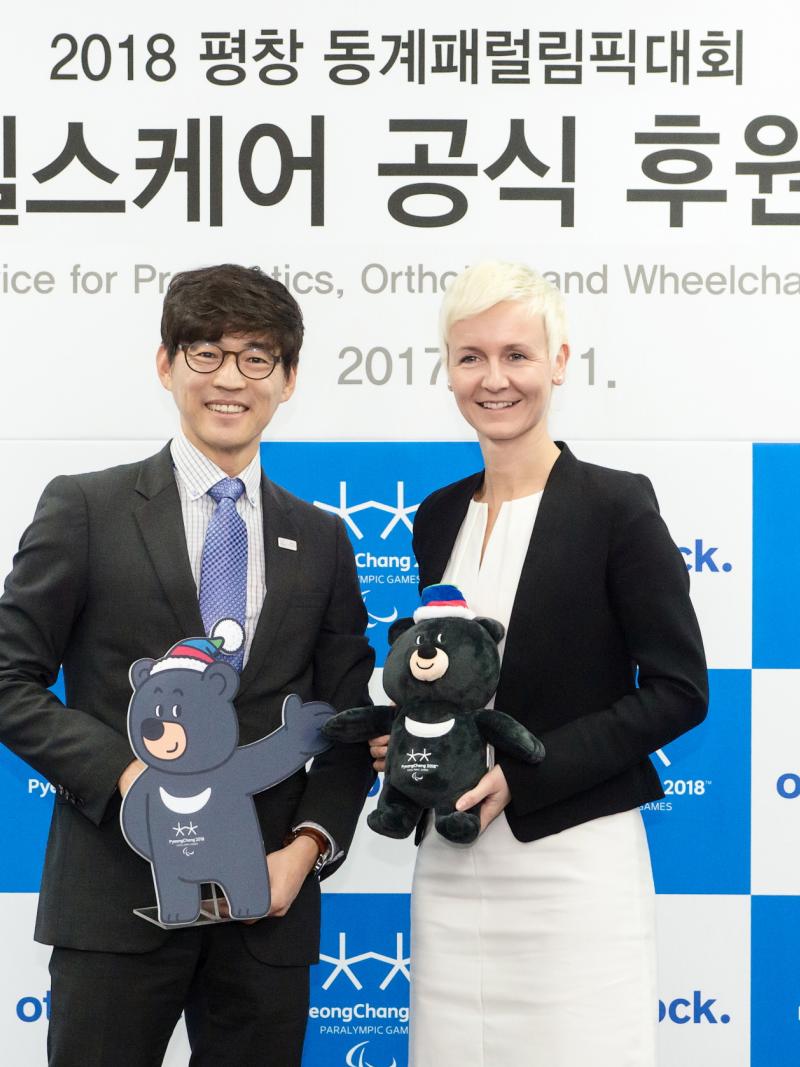 a man and a woman standing holding mascots