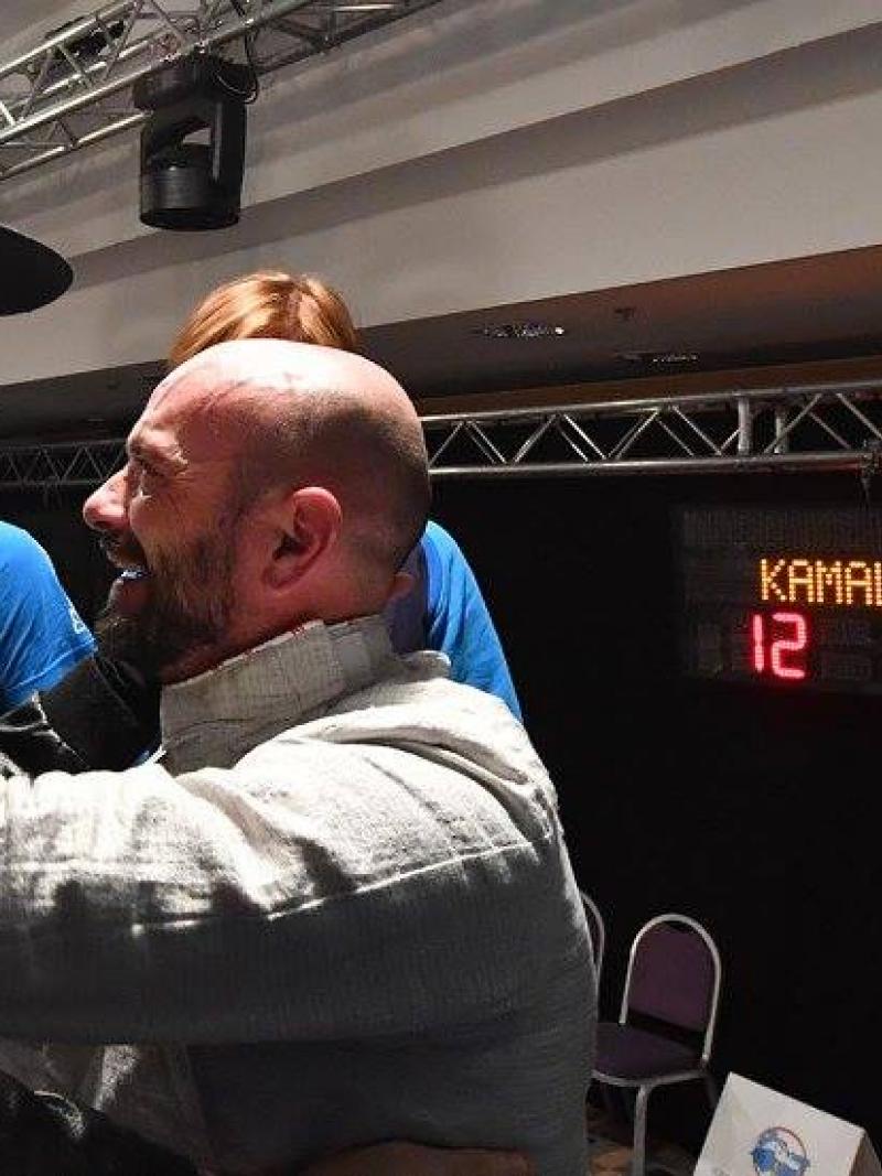 Two men celebrating and hugging in front of an electronic scoreboard