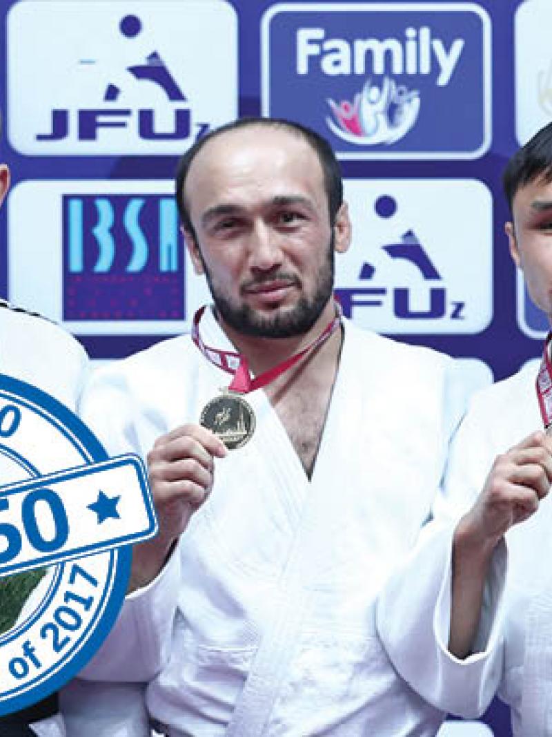 a group of four judokas stand smiling on the podium