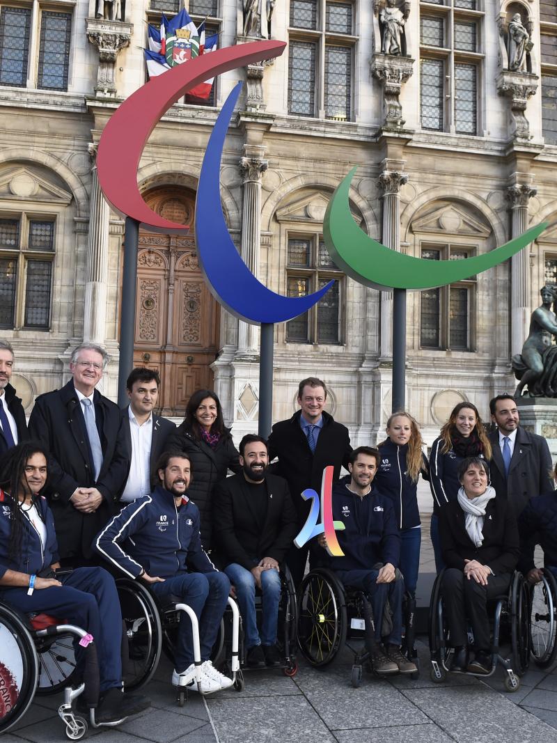 Group of people smiling in front of the Agitos logo and the municipality of Paris