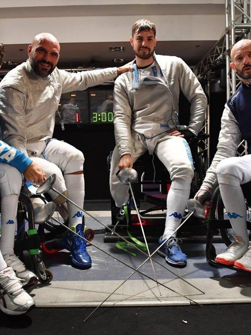 Four male wheelchair fencers pose with their swords 