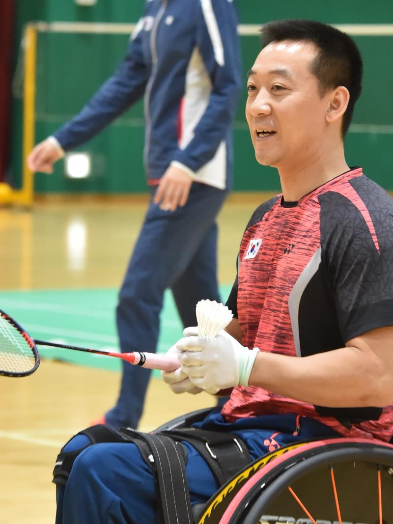 A male Para badminton player holds a shuttlecock and racquet