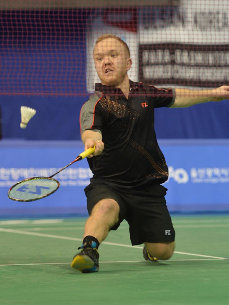 a male Para badminton player goes for a shot