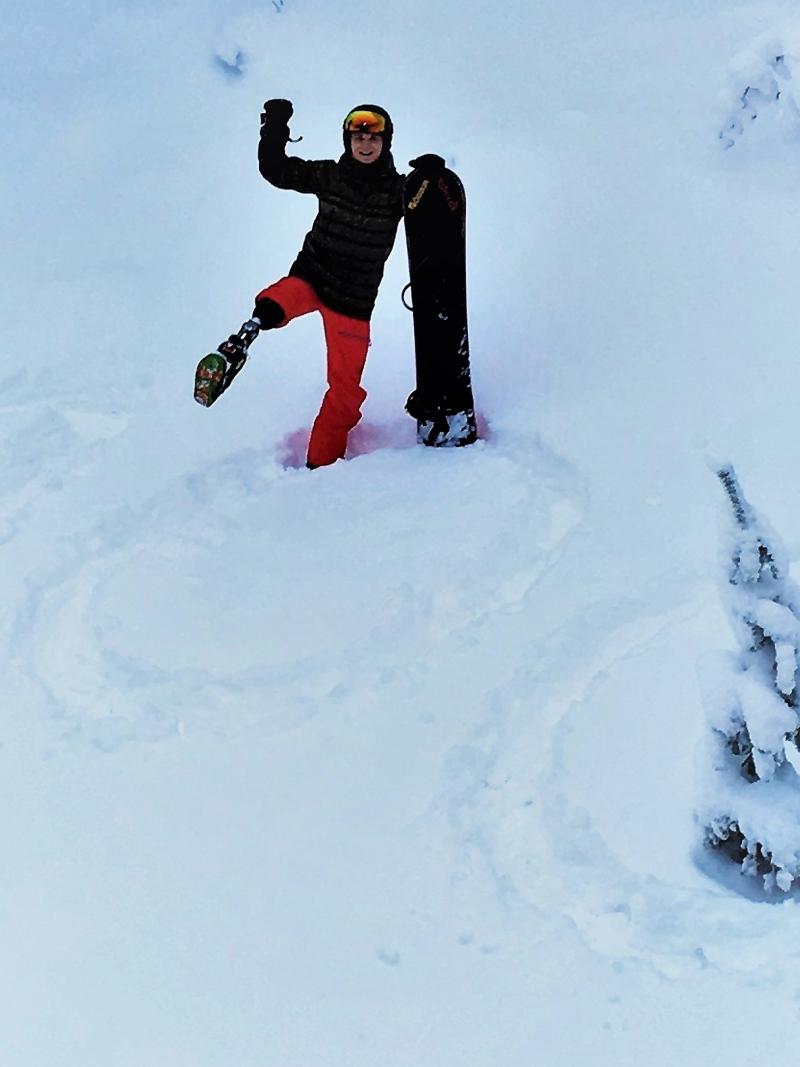 a male Para snowboarder stands on a '100' drawn in the snow