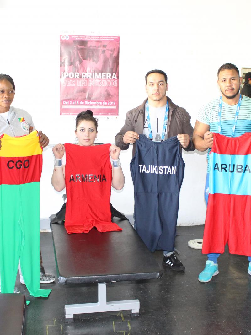 a group of Para powerlifters hold up their lifting suits