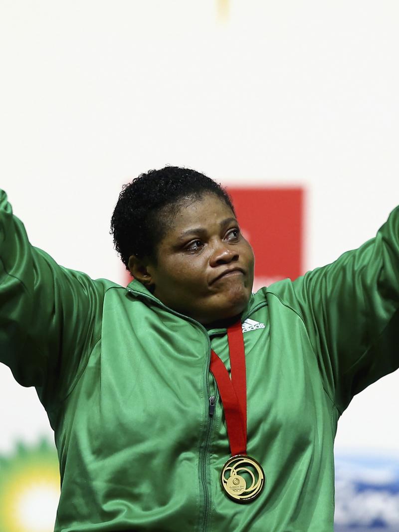 a female powerlifter raises her arms in celebration