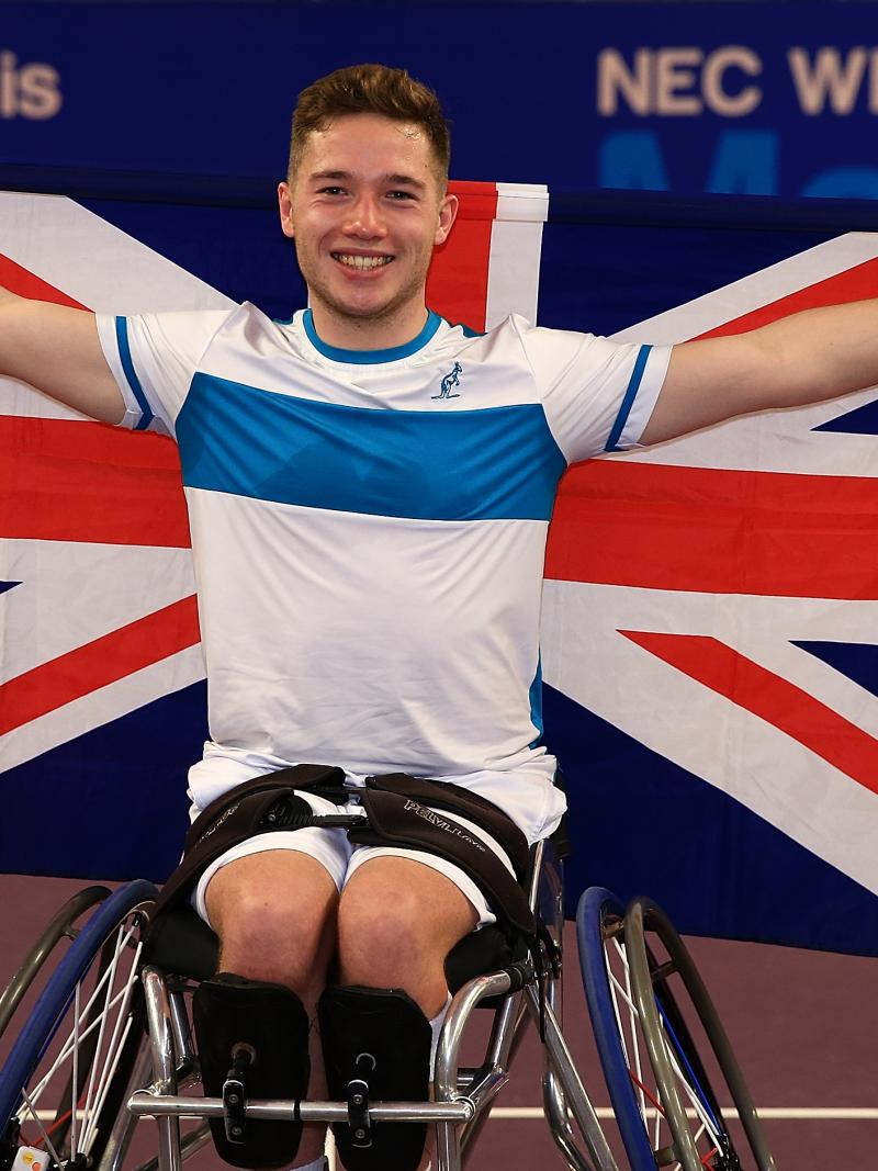 a male wheelchair tennis player holds up the Union Jack