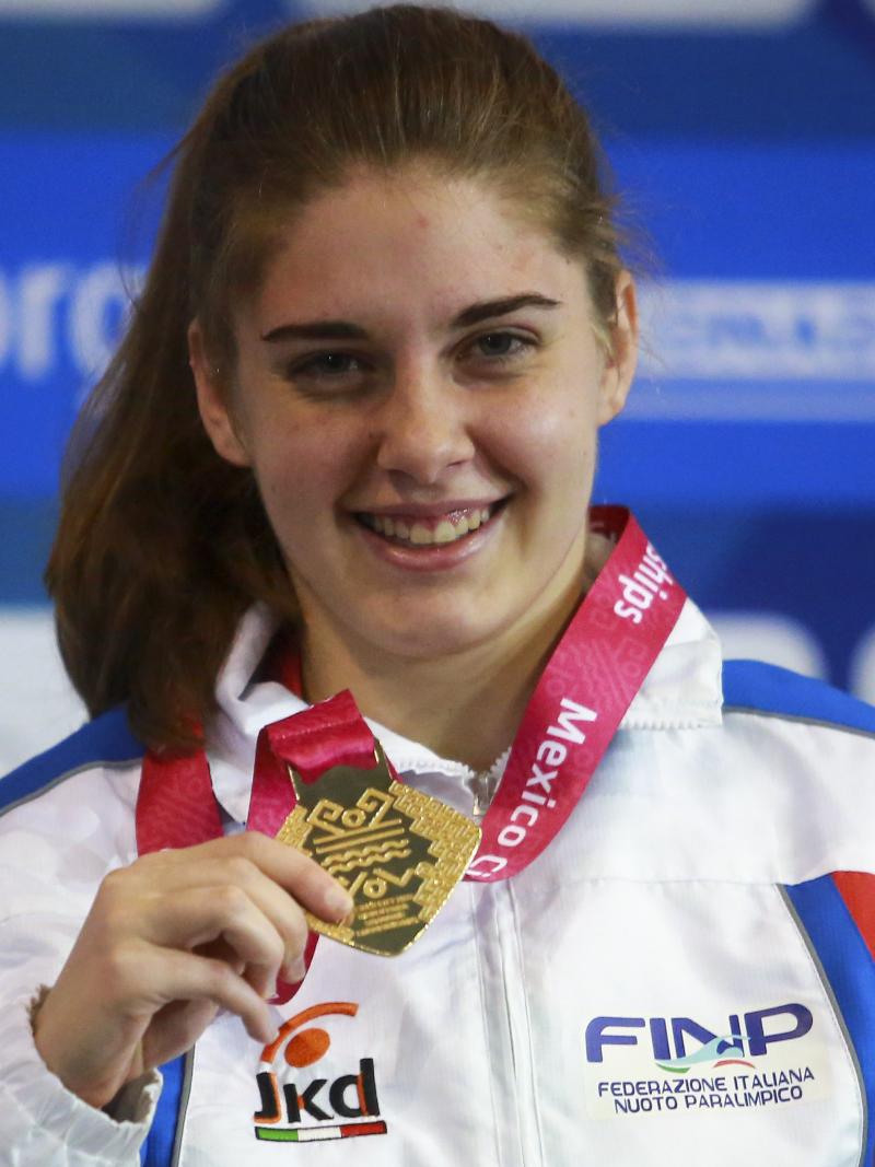 a female Para swimmer holds up her gold medal and smiles
