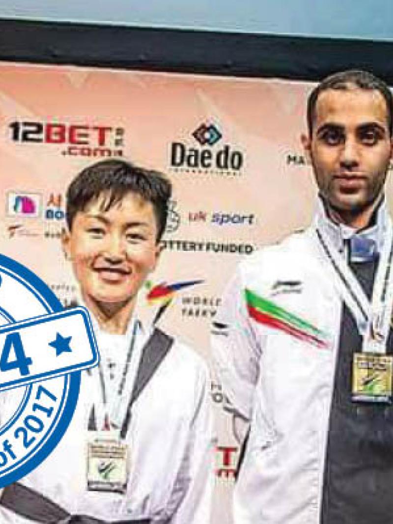 a female Para taekwondo fighter raises her trophy and smiles