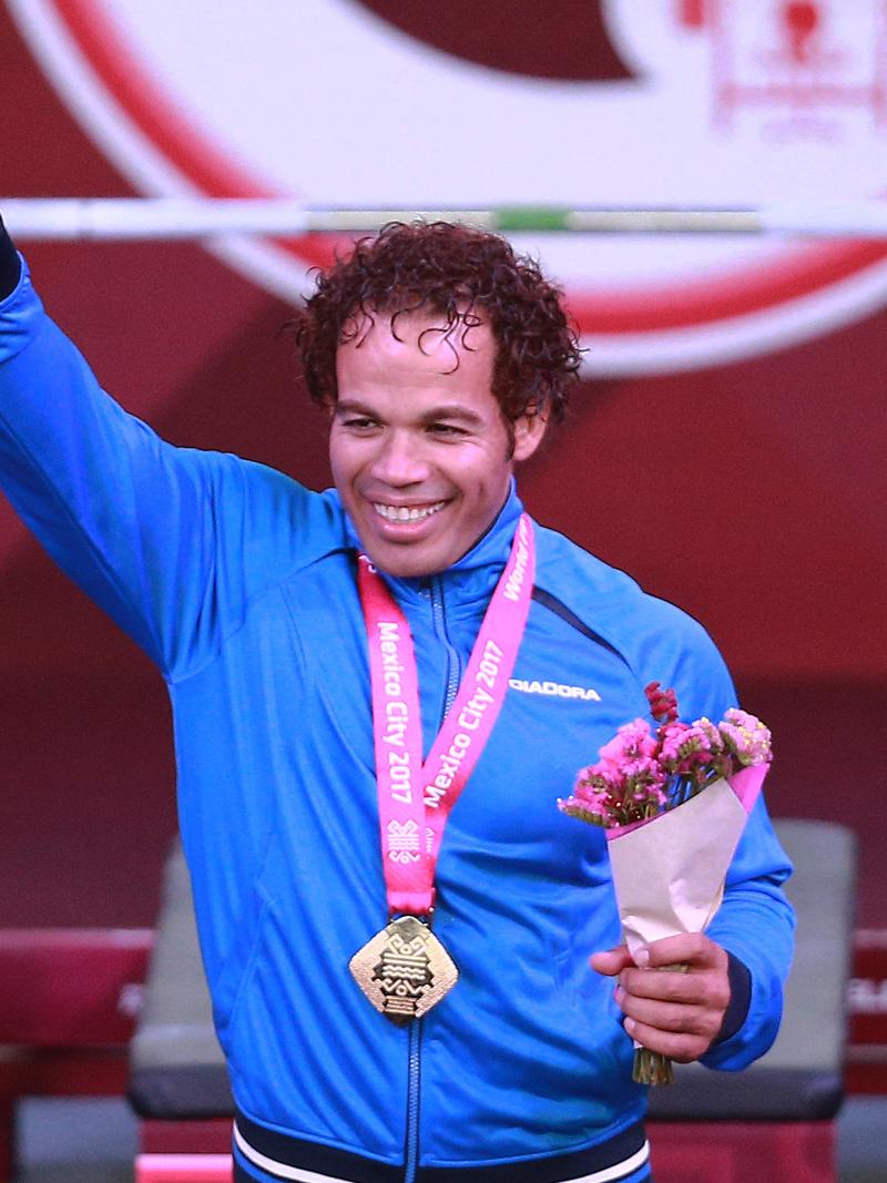a male powerlifter celebrates his gold medal on the podium